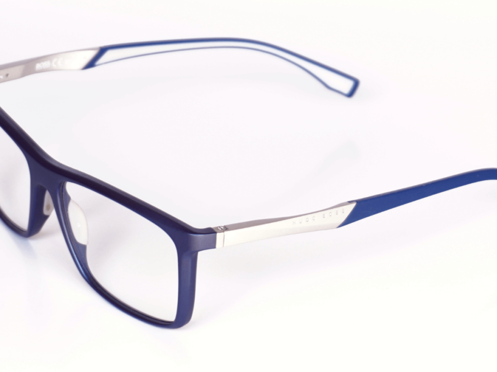 Un par de gafas de sol redondas con lentes azules. Las gafas están colocadas sobre una mesa blanca.