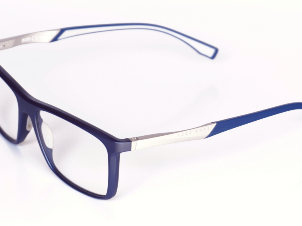 Entendiendo el 脕ngulo pantosc贸pico de las gafas 2 Un par de gafas de sol redondas con lentes azules. Las gafas est谩n colocadas sobre una mesa blanca.
